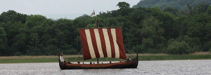 A longship sails over calm waters © Regia Anglorum – Lauren Roberts
